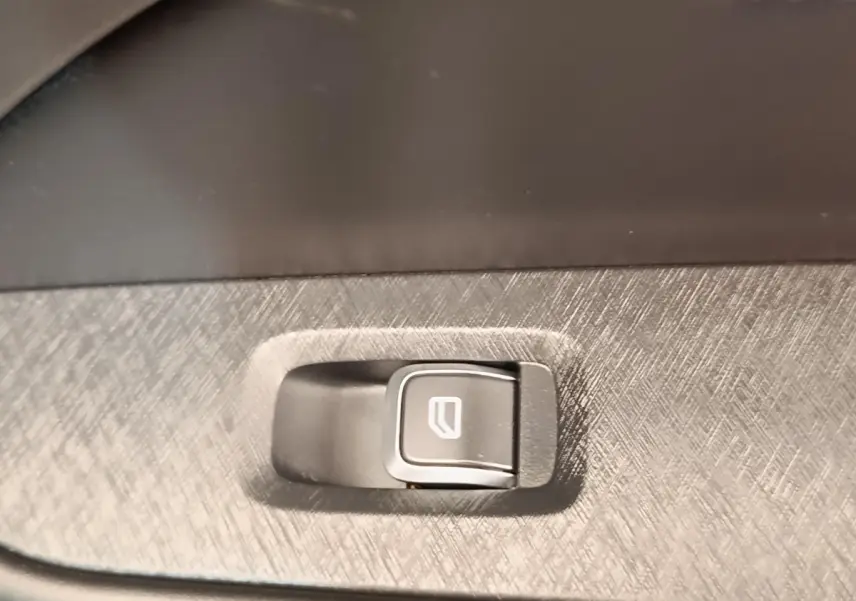 Gros plan sur bouton de lève-vitre intégré dans panneau intérieur gris texturé d’un Link & Co 01 bleu.