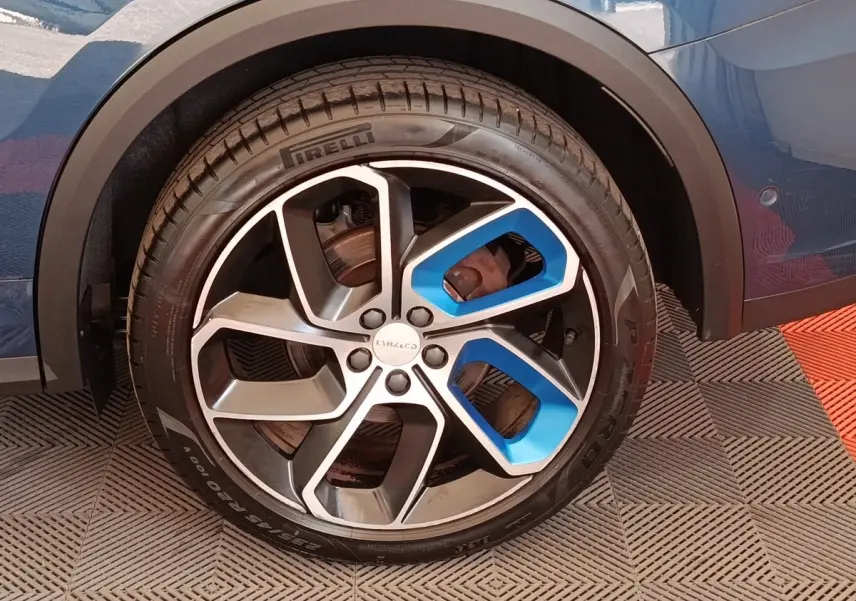 Gros plan sur la roue arrière droite bleu métallisé du Lynk & Co 01 avec jante alliage noire et bleue.