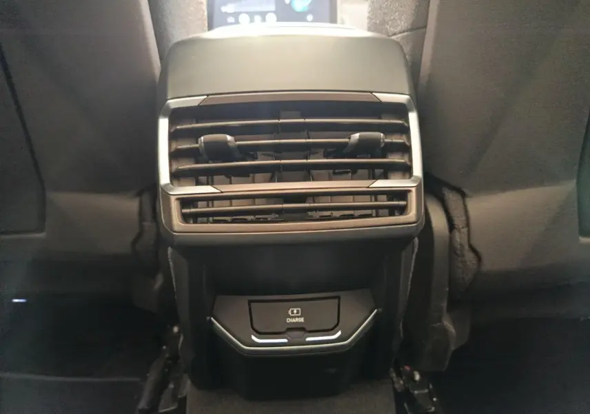 Vue rapprochée de la console arrière avec prise de charge sans fil et aérateurs du LINK & CO 01 bleu 2023.