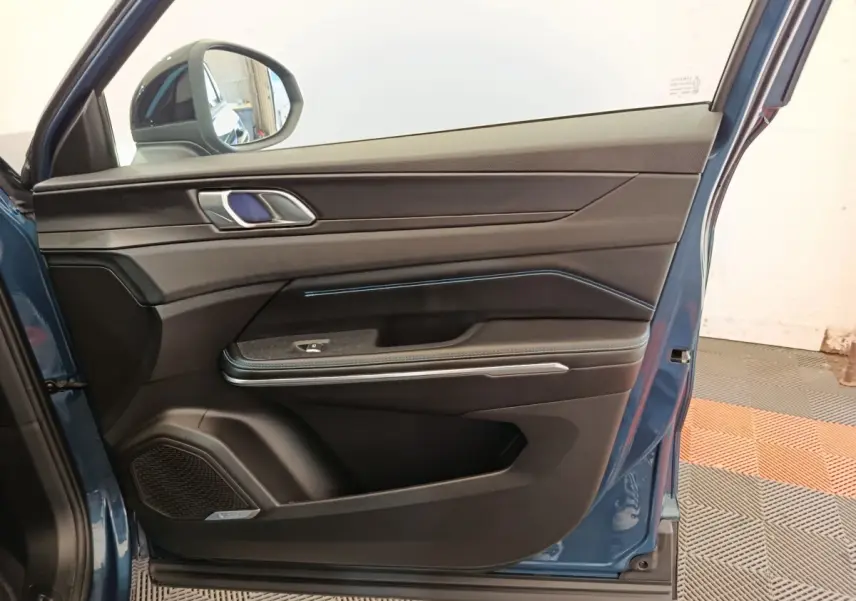 Vue intérieure de la porte avant gauche bleu du LINK & CO 01 hybride rechargeable avec garniture noire et éclairage d'ambiance bleu.