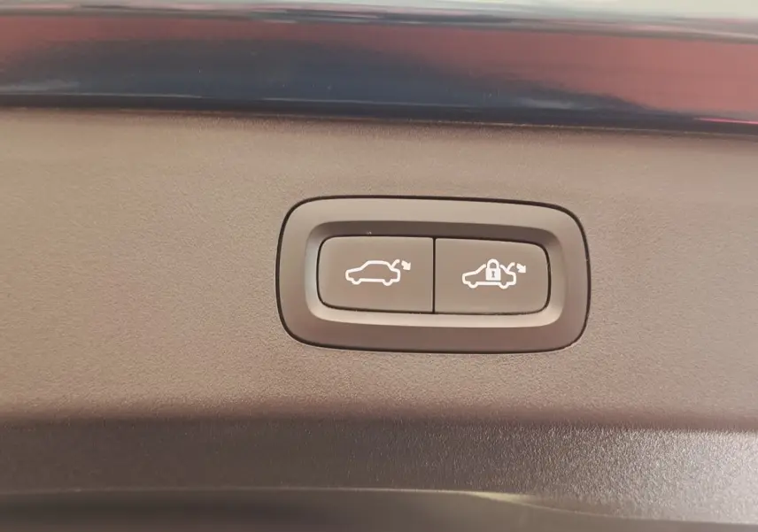 Gros plan sur les boutons d'ouverture et de verrouillage électrique du coffre du SUV bleu LINK & CO 01 hybride rechargeable.