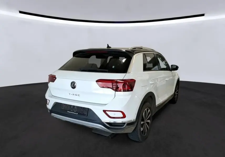 Volkswagen T-Roc blanc pur avec toit noir, vue 3/4 arrière droit, mettant en valeur ses feux arrière et jantes 17 pouces.