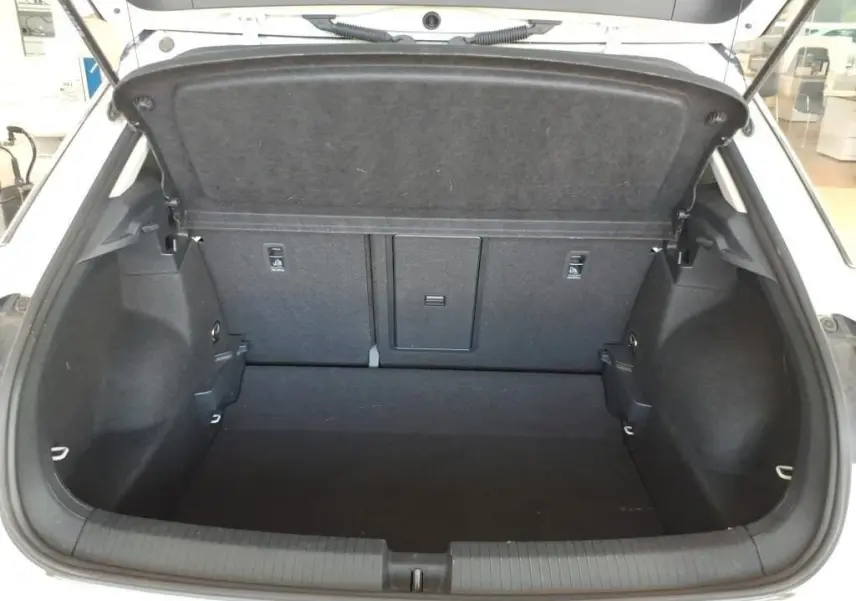 Vue intérieure du coffre ouvert du Volkswagen T-Roc blanc pur avec toit noir, montrant un espace de chargement propre et spacieux.