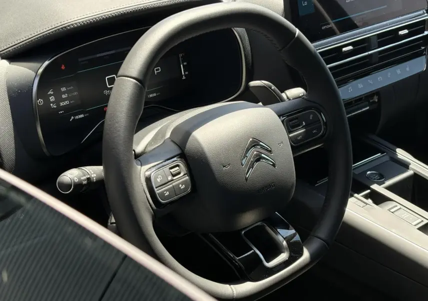 Vue rapprochée du volant cuir noir et du combiné numérique de la Citroën C5 Aircross Hybrid 2025, intérieur moderne et épuré.