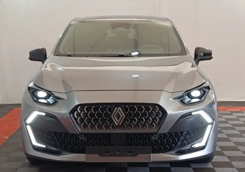 Vue frontale d'une Renault Clio Techno gris foncé avec phares et feux LED allumés, calandre hexagonale distinctive.