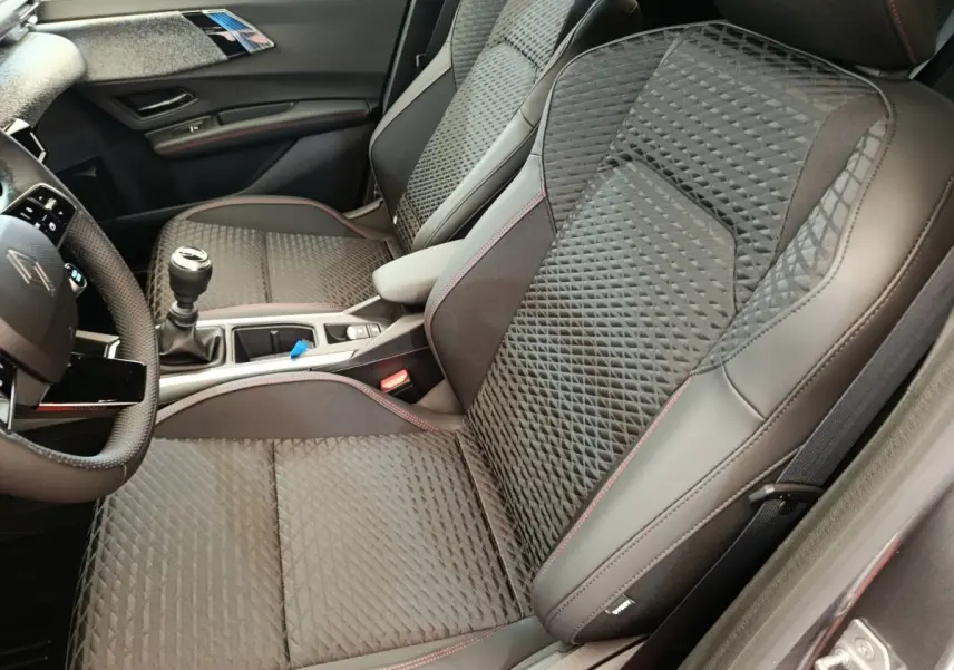 Vue intérieure côté droit des sièges avant gris foncé avec surpiqûres rouges et console centrale d'une Renault Clio Techno TCe 115 2026.