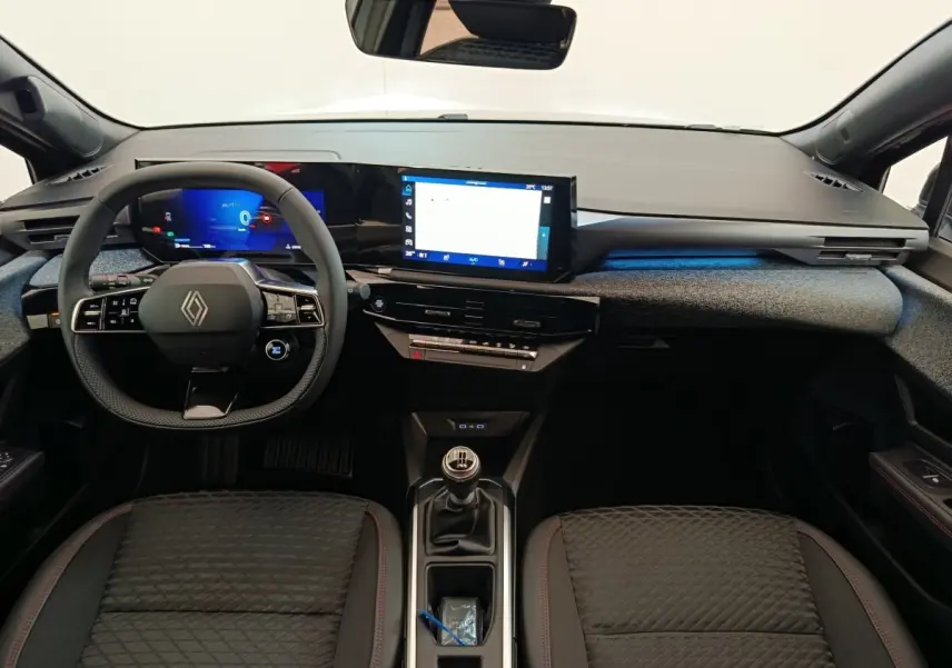 Vue intérieure avant de la Renault Clio Techno TCe 115 gris foncé, tableau de bord moderne avec écran tactile et volant multifonctions.