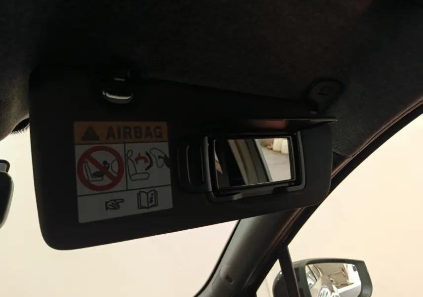 Détail du pare-soleil côté conducteur avec miroir de courtoisie ouvert et avertissement airbag visible dans une Renault Clio 2026.