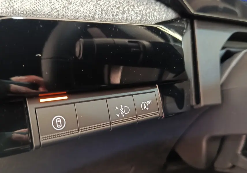 Détail intérieur montrant les boutons de réglage des phares et désactivation du start/stop sur tableau de bord noir.