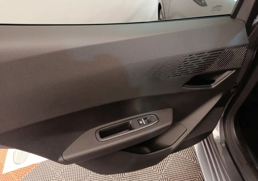Vue rapprochée de la porte avant droite intérieure de la Renault Clio gris foncé, avec commandes de vitre électrique.