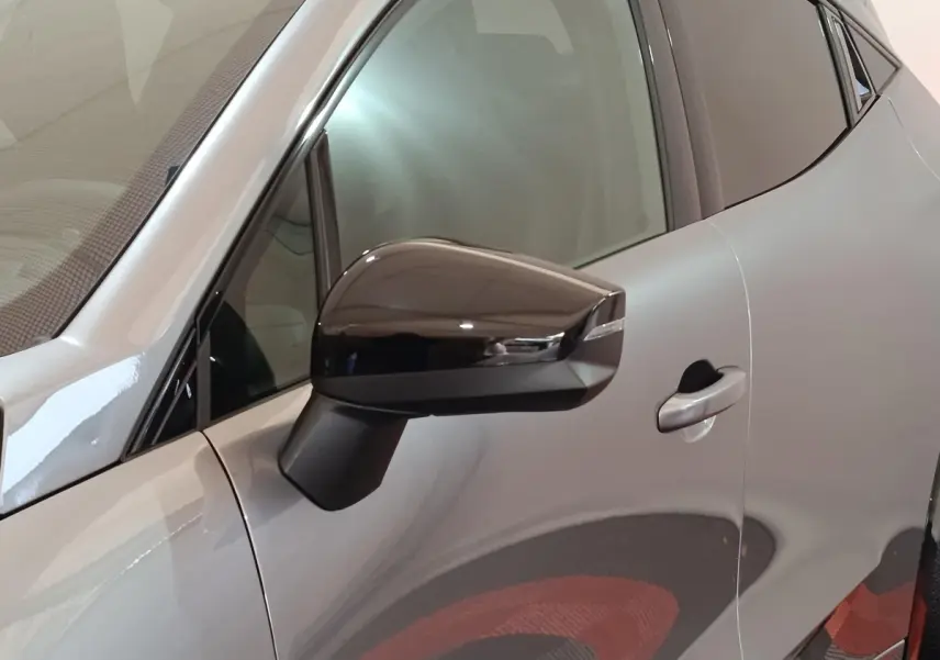 Vue rapprochée du côté gauche d'une Renault Clio Techno gris foncé, mettant en valeur le rétroviseur noir brillant et la poignée de porte.