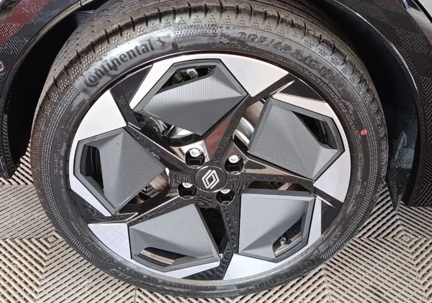 Gros plan sur la roue avant droite de la Renault Clio gris foncé, jante au design géométrique noir et argent.
