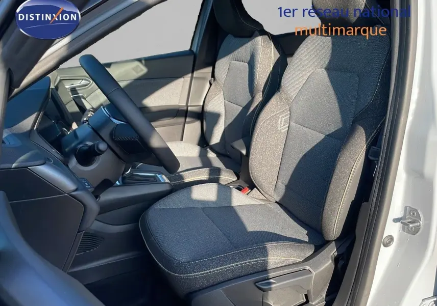 Intérieur avant droit du Renault Captur E-Tech 2025 avec sièges tissu gris et volant noir visible au soleil.