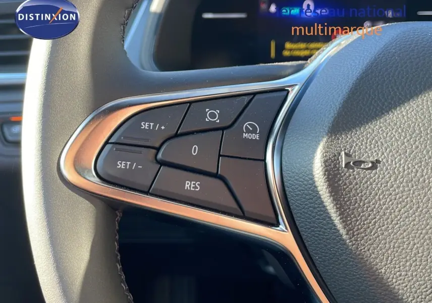 Gros plan sur les commandes au volant du Renault Captur E-Tech gris rafale, soulignant les boutons de régulateur de vitesse.