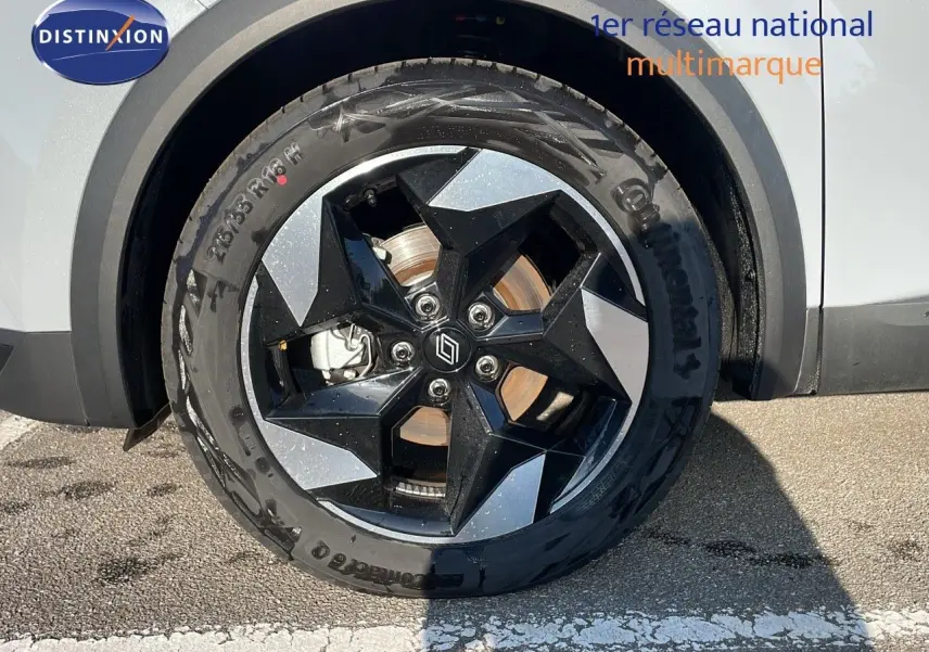 Gros plan sur la roue avant droite du Renault Captur gris Rafale avec jante noire et argentée au design géométrique.