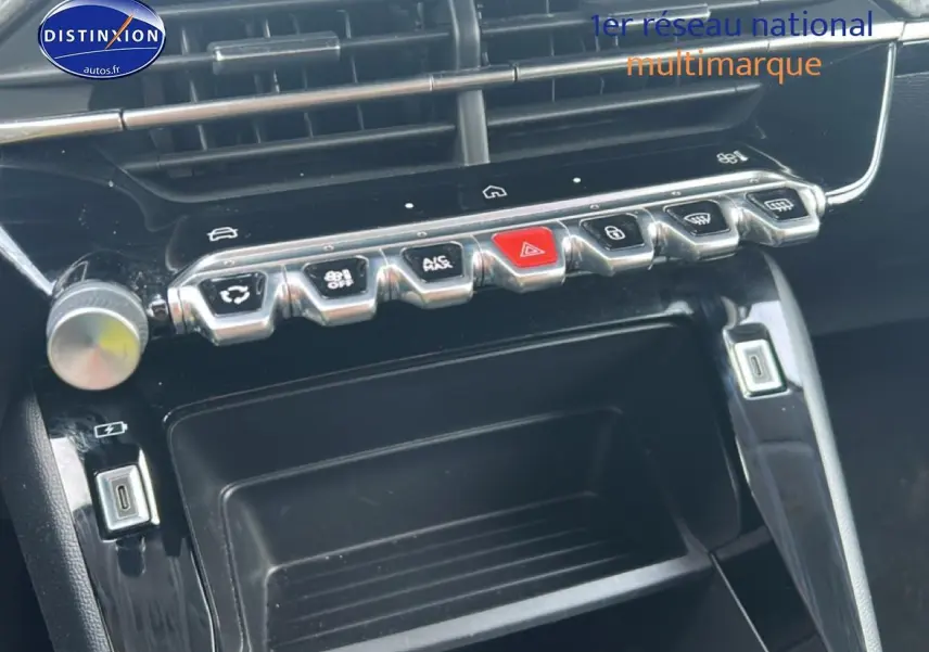 Vue rapprochée de la console centrale noire de la Peugeot 208 1.2 100 style avec boutons de commande chromés.
