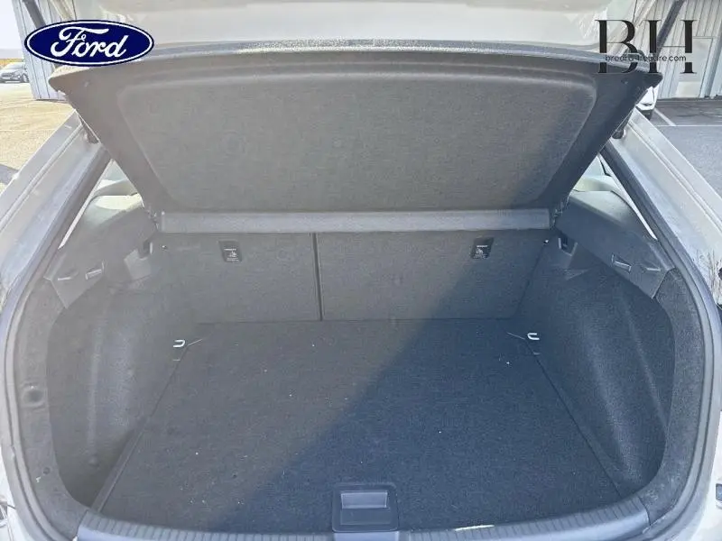 Coffre ouvert vu de l'arrière d'un Volkswagen Taigo blanc pur, espace de chargement vide et tapis noir.