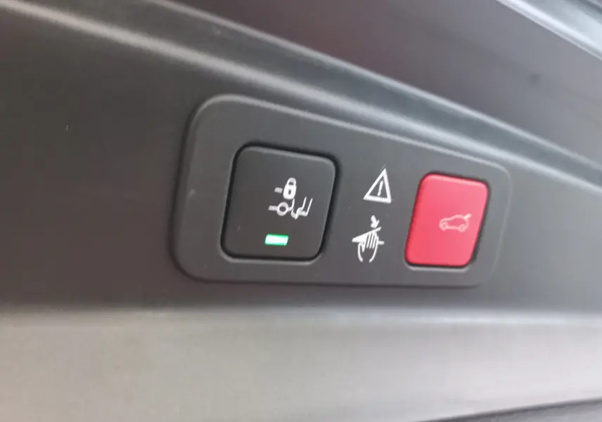 Gros plan sur les boutons de commande du hayon et sécurité dans un Peugeot 5008 gris foncé, intérieur coffre.