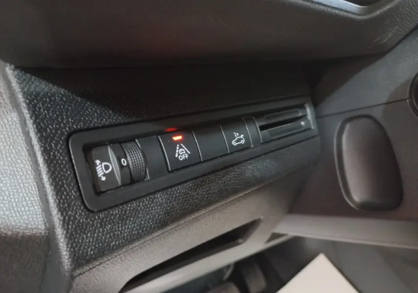 Gros plan sur les commandes d'assistance et réglage des phares côté gauche du tableau de bord noir du Peugeot 5008 gris foncé.