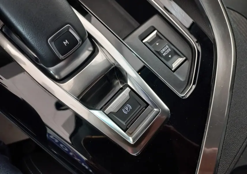 Gros plan sur la console centrale noire brillante du Peugeot 5008 2021 avec bouton frein électrique et sélecteur Drive Mode.