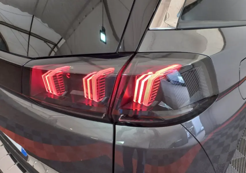 Gros plan sur le feu arrière droit rouge d’un Peugeot 5008 gris foncé, soulignant le design moderne du véhicule.