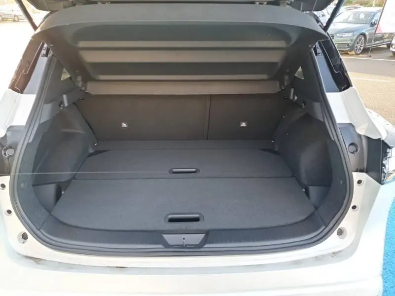 Coffre ouvert vu de l'arrière du Nissan Qashqai blanc nacré toit noir, montrant un espace de chargement plat et spacieux.