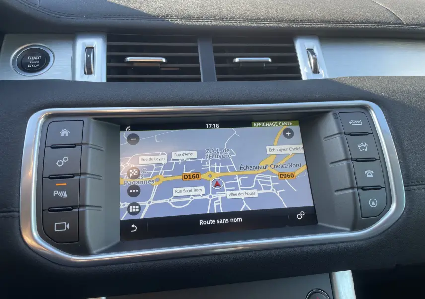 Gros plan sur l’écran tactile GPS intégré au tableau de bord noir du Range Rover Evoque 2016, avec commandes latérales.