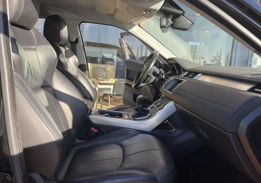 Intérieur noir cuir du Range Rover Evoque 2016, vue côté conducteur avec tableau de bord et levier de vitesses manuel.