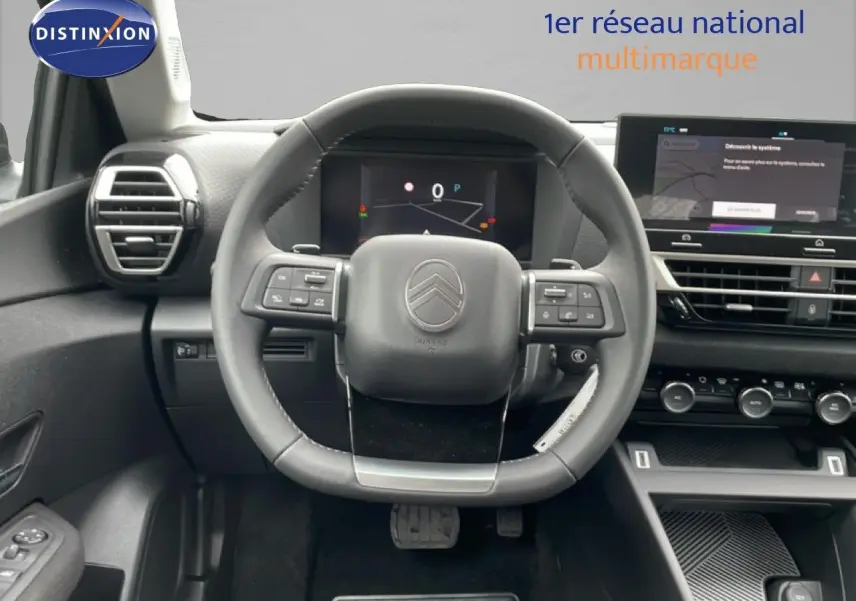 Vue intérieure centrée sur le volant multifonction d'une Citroën C4 blanc métal avec tableau de bord numérique et écran tactile.