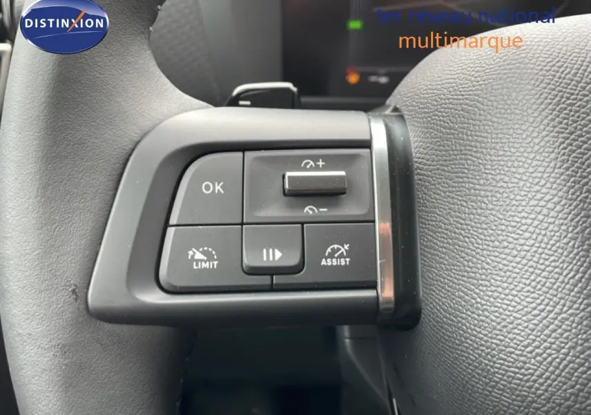 Gros plan sur les commandes au volant à gauche du Citroën C4 blanc métal, avec boutons de limitation et assistance.