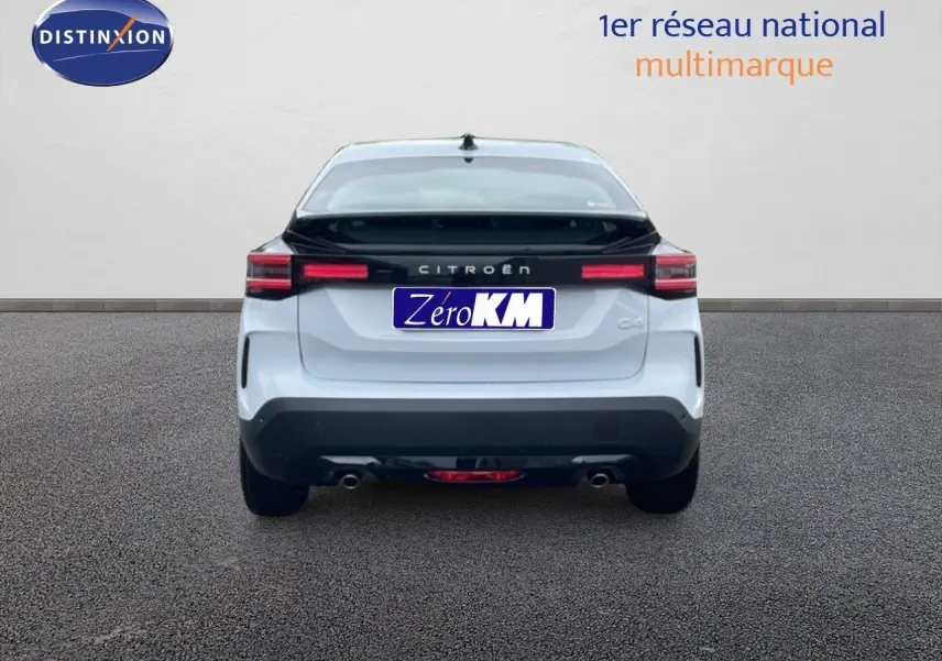 Vue arrière d'une Citroën C4 blanche métallisée avec bande noire et feux arrière LED allumés.