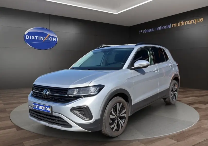 Volkswagen T-Cross gris clair en 3/4 avant droit, avec jantes alliage et calandre noire distinctive.