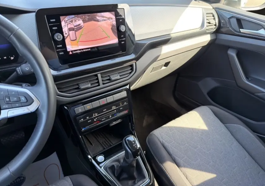 Vue intérieure côté passager du Volkswagen T-Cross gris clair 2025, avec écran tactile affichant la caméra de recul.