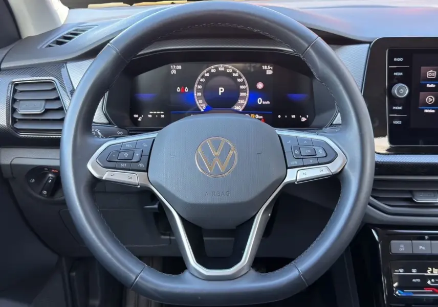 Vue rapprochée du volant cuir noir Volkswagen T-Cross 2025 avec tableau de bord numérique et écran tactile central.