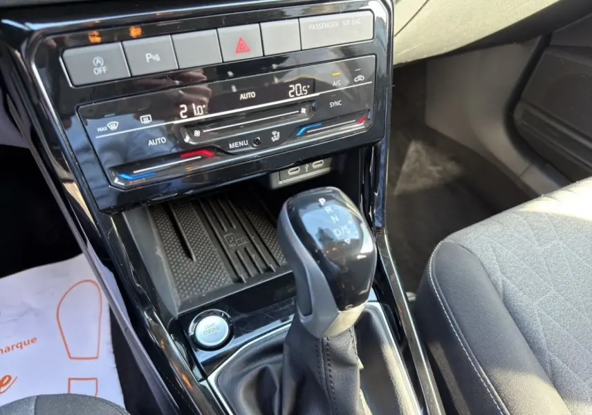 Gros plan sur la console centrale du Volkswagen T-Cross 2025, avec levier de boîte auto et commandes climatisation tactile.