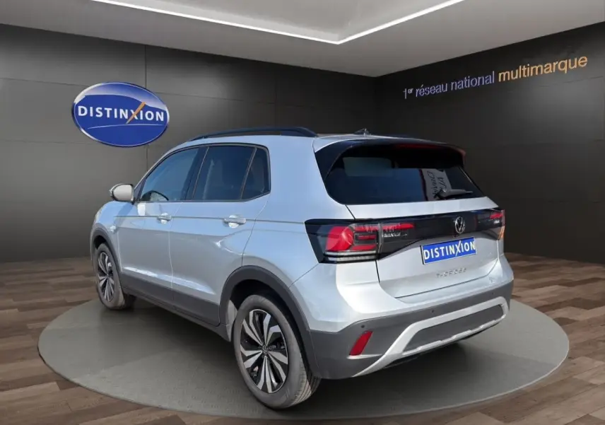 Vue 3/4 arrière droite d’un Volkswagen T-Cross gris clair avec feux arrière LED et jantes alliage bicolores.