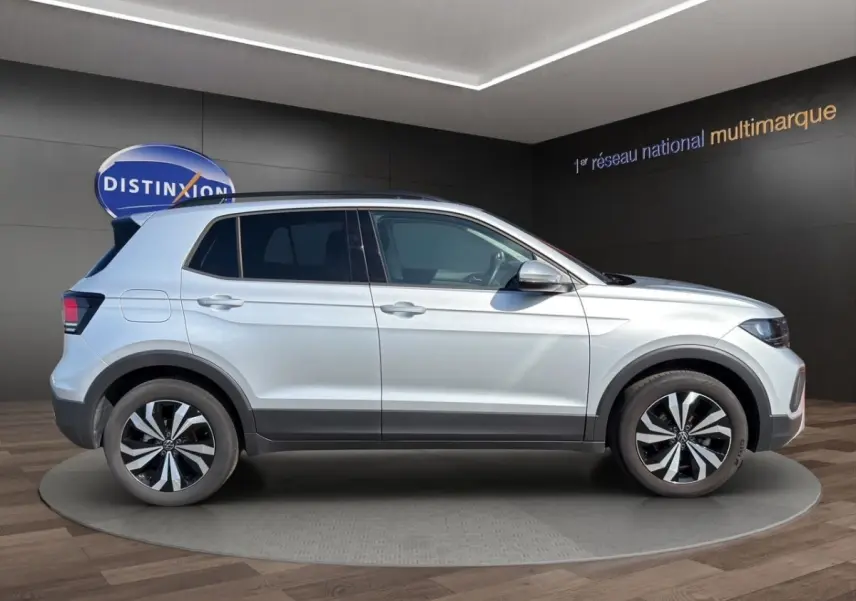 Vue latérale droite d'un Volkswagen T-Cross gris clair 2025 avec jantes alliage bicolores et toit noir.