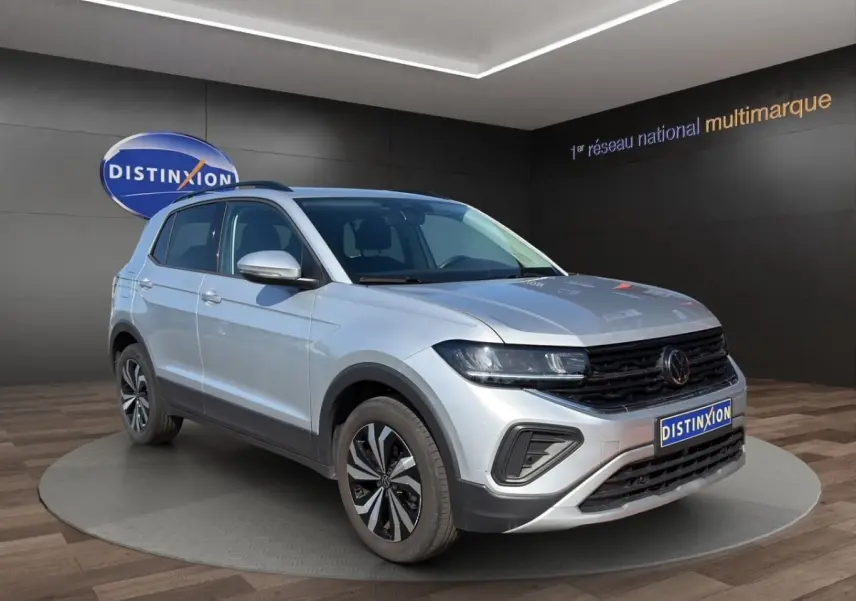 Volkswagen T-Cross gris clair vue 3/4 avant droit, avec calandre noire et jantes alliage distinctives.