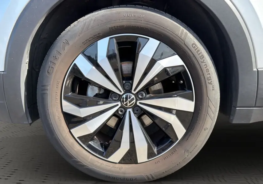 Gros plan sur la roue avant droite du Volkswagen T-Cross gris clair avec jante alliage bicolore distinctive.