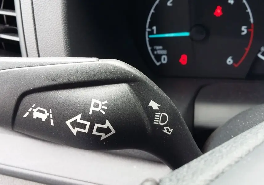 Gros plan sur le commodo de clignotants du Ford Transit Fourgon blanc, avec tableau de bord en arrière-plan.