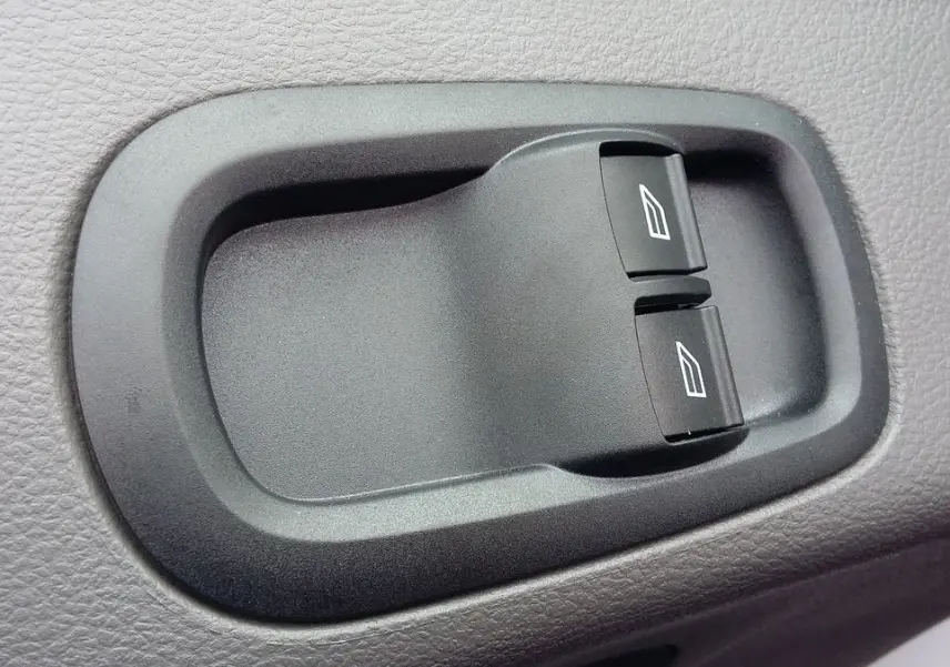 Gros plan sur les commandes électriques des vitres du côté conducteur du Ford Transit Fourgon blanc glacier 2022.