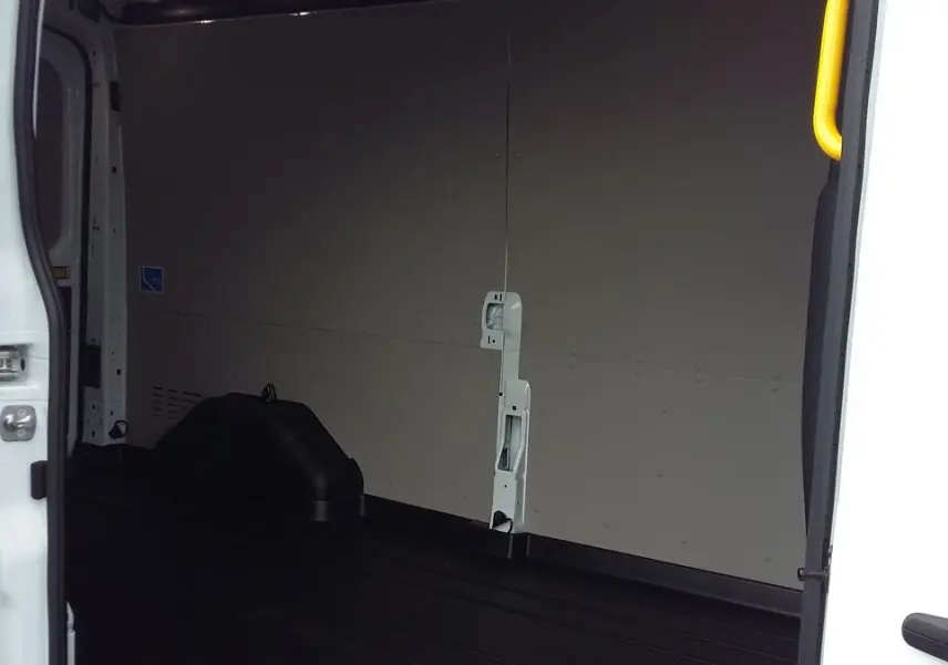 Vue intérieure côté gauche du fourgon Ford Transit blanc glacier, montrant l'espace de chargement vide et les parois claires.