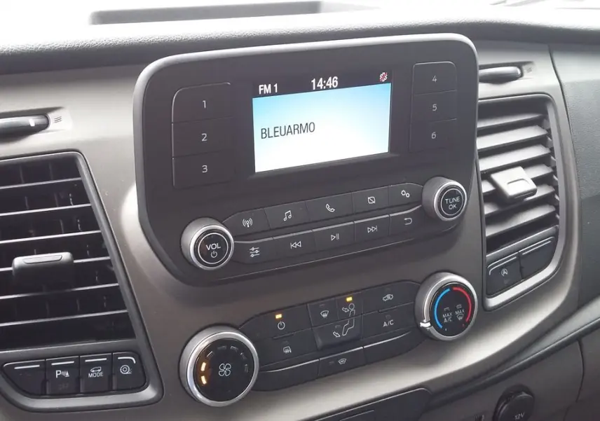 Vue rapprochée du tableau de bord du Ford Transit Fourgon 2022, avec commandes audio et climatisation visibles.