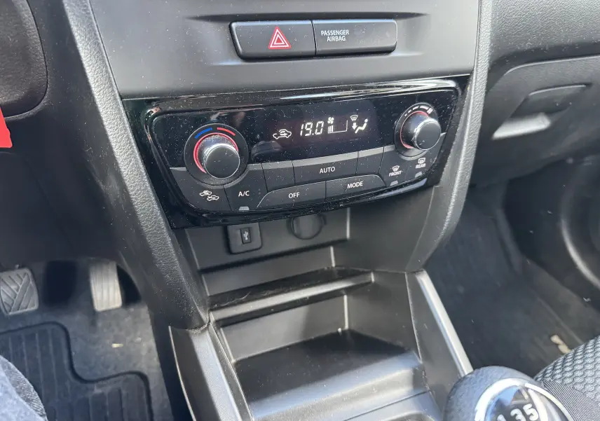 Vue rapprochée de la console centrale du Suzuki Vitara blanc 2023, montrant la climatisation automatique et le levier de vitesses manuel.