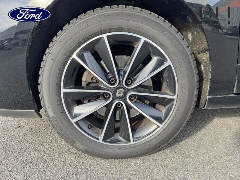 Gros plan sur la jante alu 17 pouces noire et argentée d'un Renault Grand Scenic noir étoilé, avec logo Renault central.