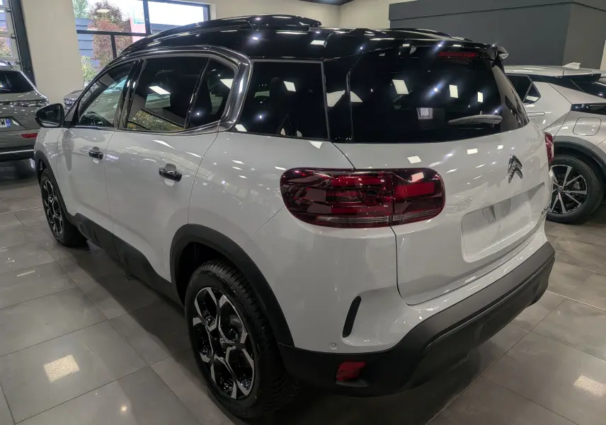 Vue 3/4 arrière droite d'un Citroën C5 Aircross hybride blanc Okénite avec toit noir et jantes noires biton.