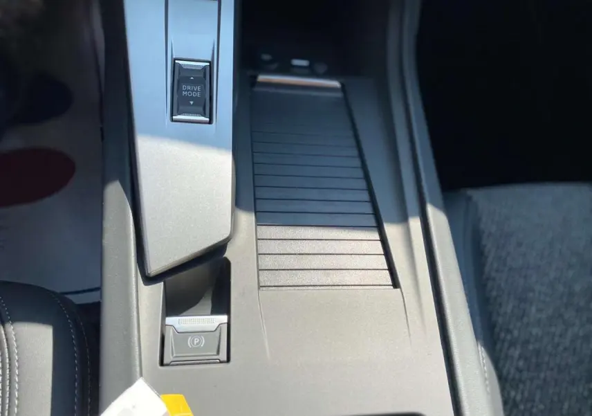 Gros plan sur la console centrale de la Peugeot 308 GT 2025 gris selenium, avec bouton Drive Mode et frein à main électrique.