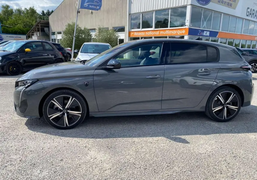 Profil côté gauche d'une Peugeot 308 GT gris selenium 2025 avec jantes noires et détails sportifs visibles.