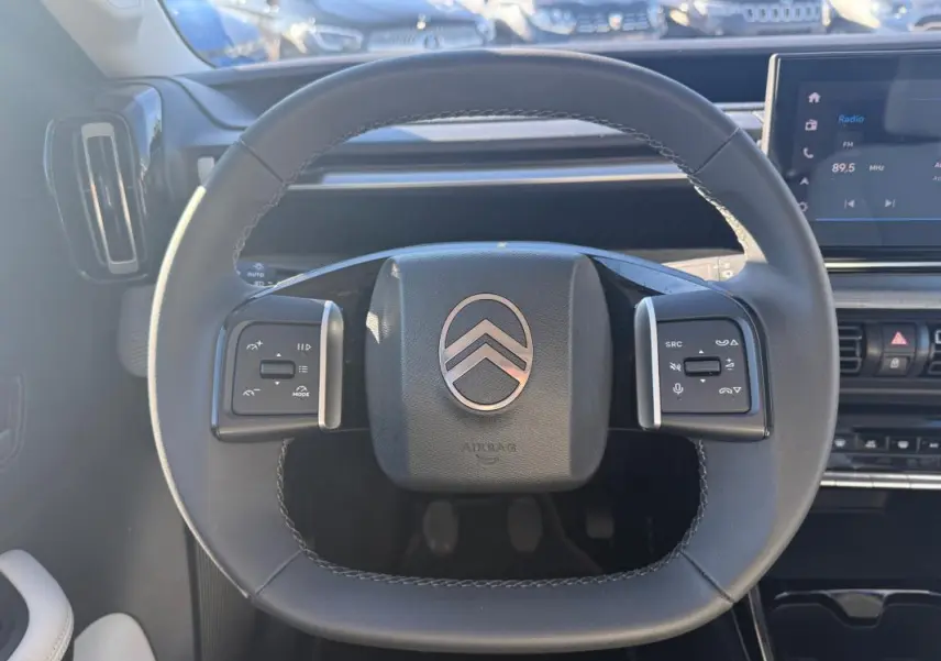 Vue rapprochée du volant noir de la Citroën C3 2025 avec commandes intégrées et tableau de bord numérique.