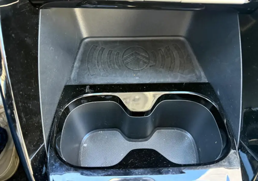 Gros plan sur le porte-gobelets noir brillant et le chargeur sans fil avec logo Citroën dans une Citroën C3 2025 gris.